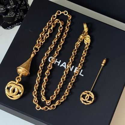 Chanel lion and coin jewelry resting on a black Chanel gift box.