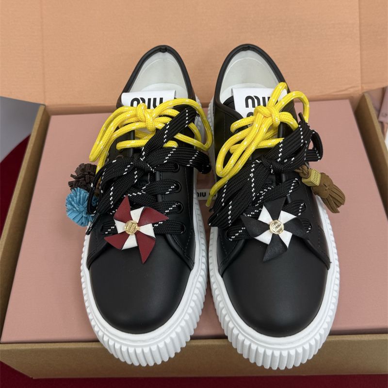 Miu Miu low-top leather sneakers with decorative laces and pinwheel embellishments.