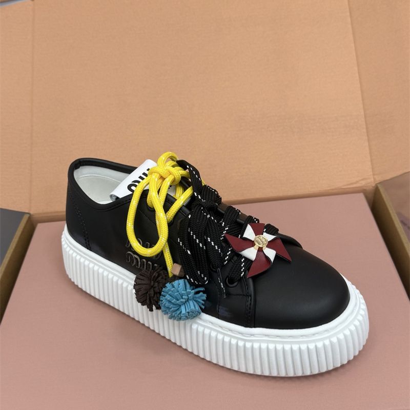 Miu Miu low-top leather sneakers with decorative laces and pinwheel embellishments.