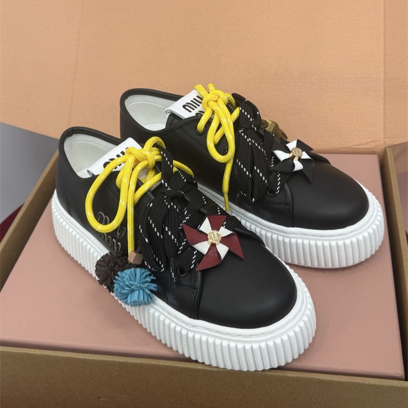 Miu Miu low-top leather sneakers with decorative laces and pinwheel embellishments.