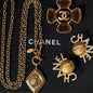 Chanel lion and coin jewelry resting on a black Chanel gift box.