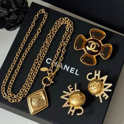 Chanel lion and coin jewelry resting on a black Chanel gift box.