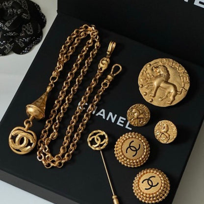 Chanel lion and coin jewelry resting on a black Chanel gift box.