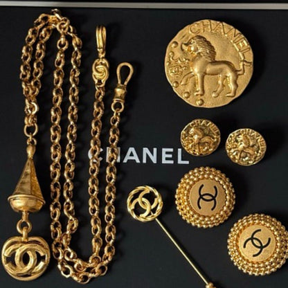 Chanel lion and coin jewelry resting on a black Chanel gift box.